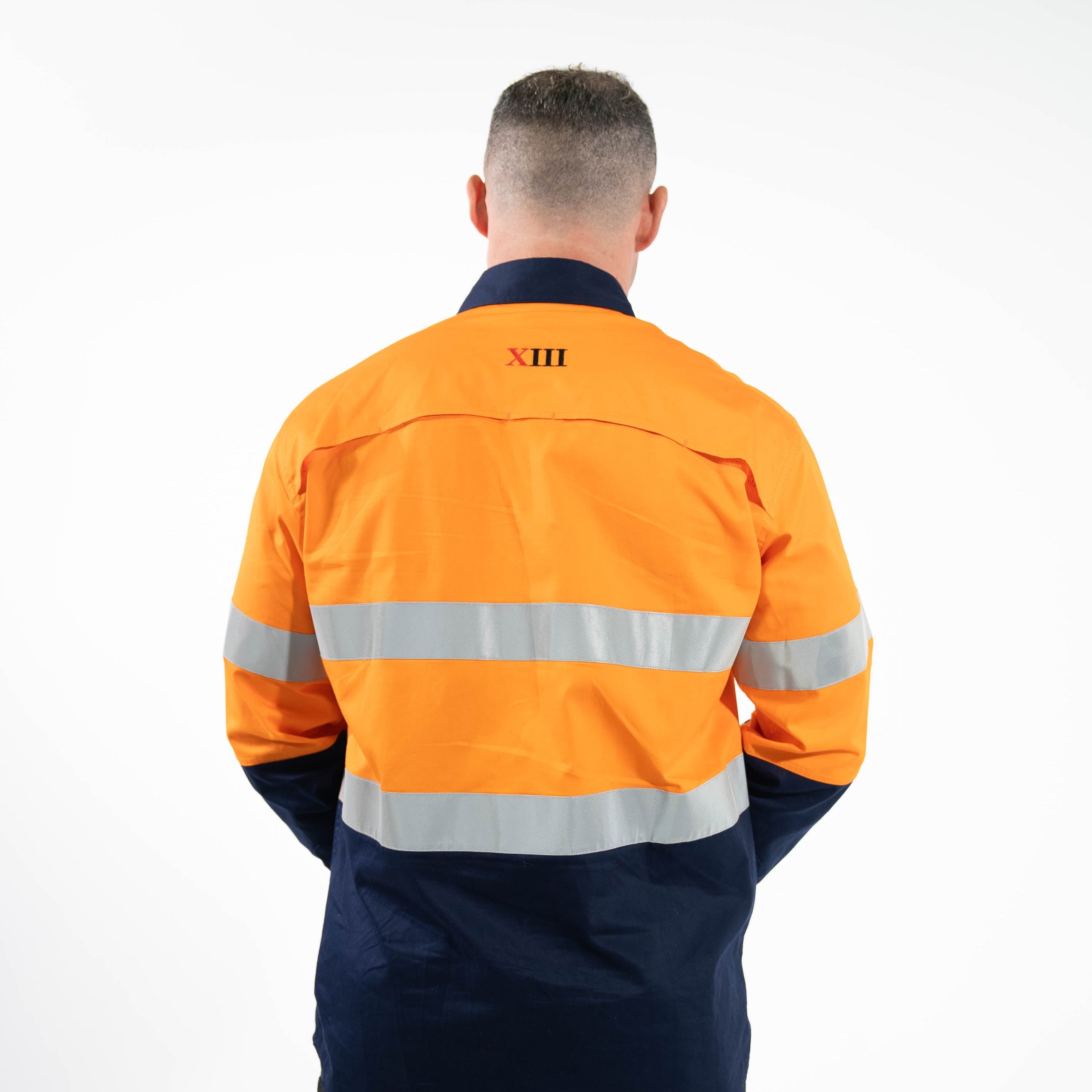 Person wearing an orange and navy work jacket with reflective stripes on a white background