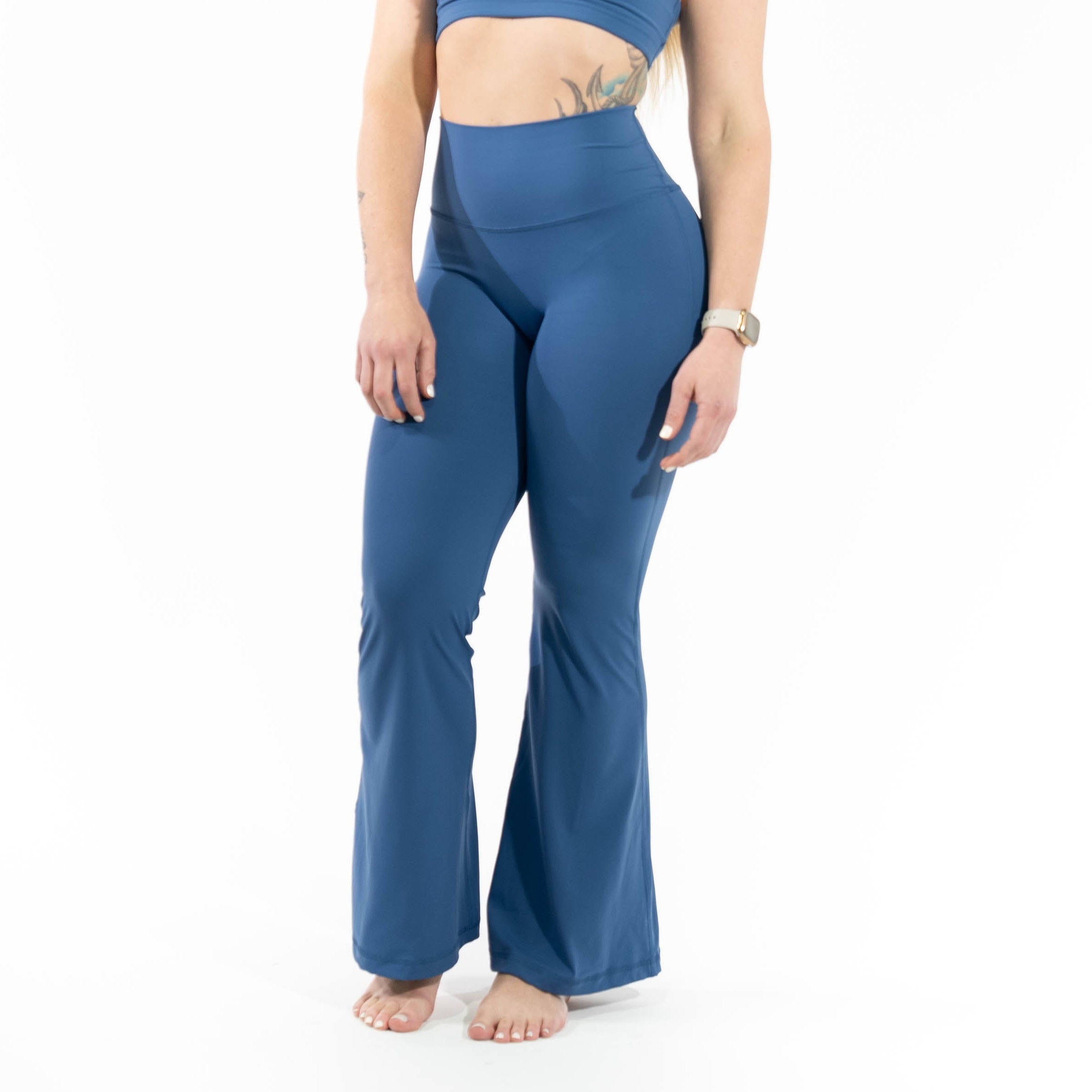 Woman wearing a blue sports bra and leggings on a white background