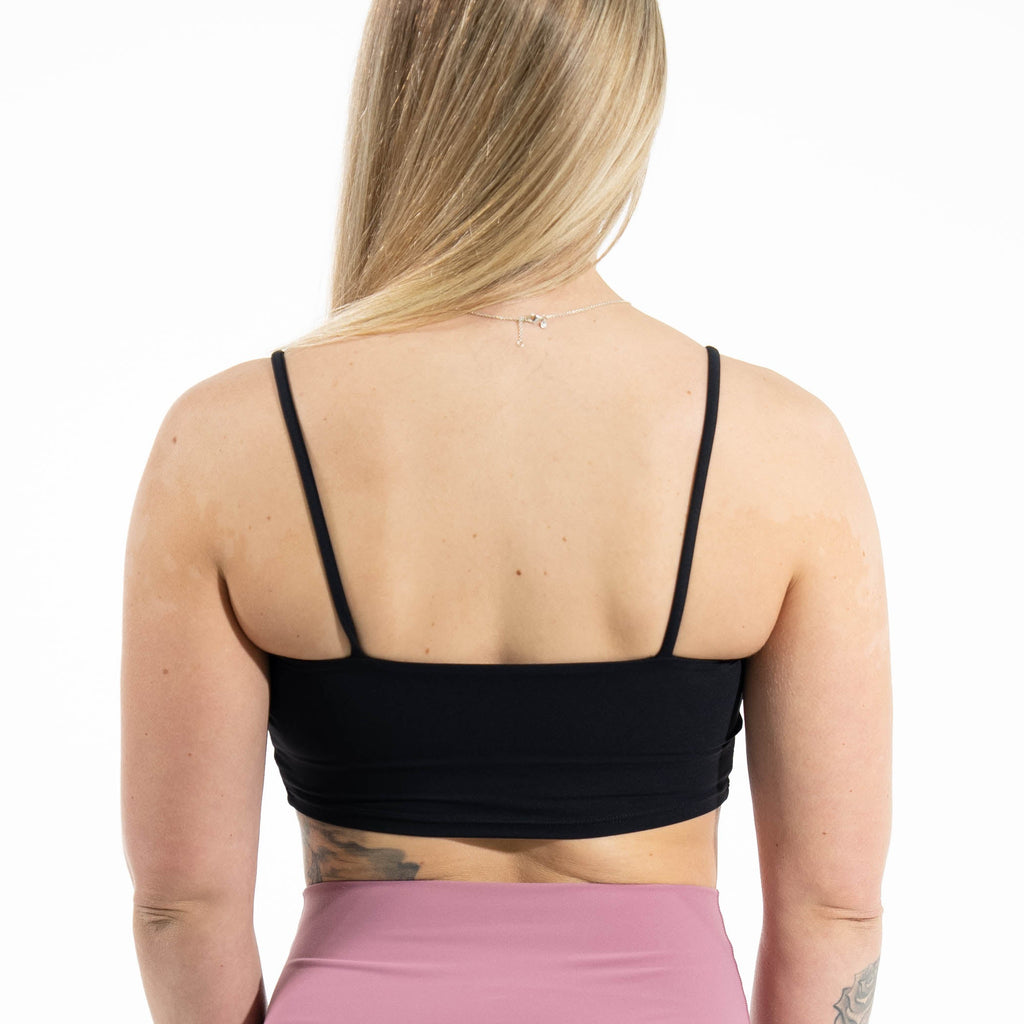 Person wearing a black sports bra and pink high-waisted shorts on a white background