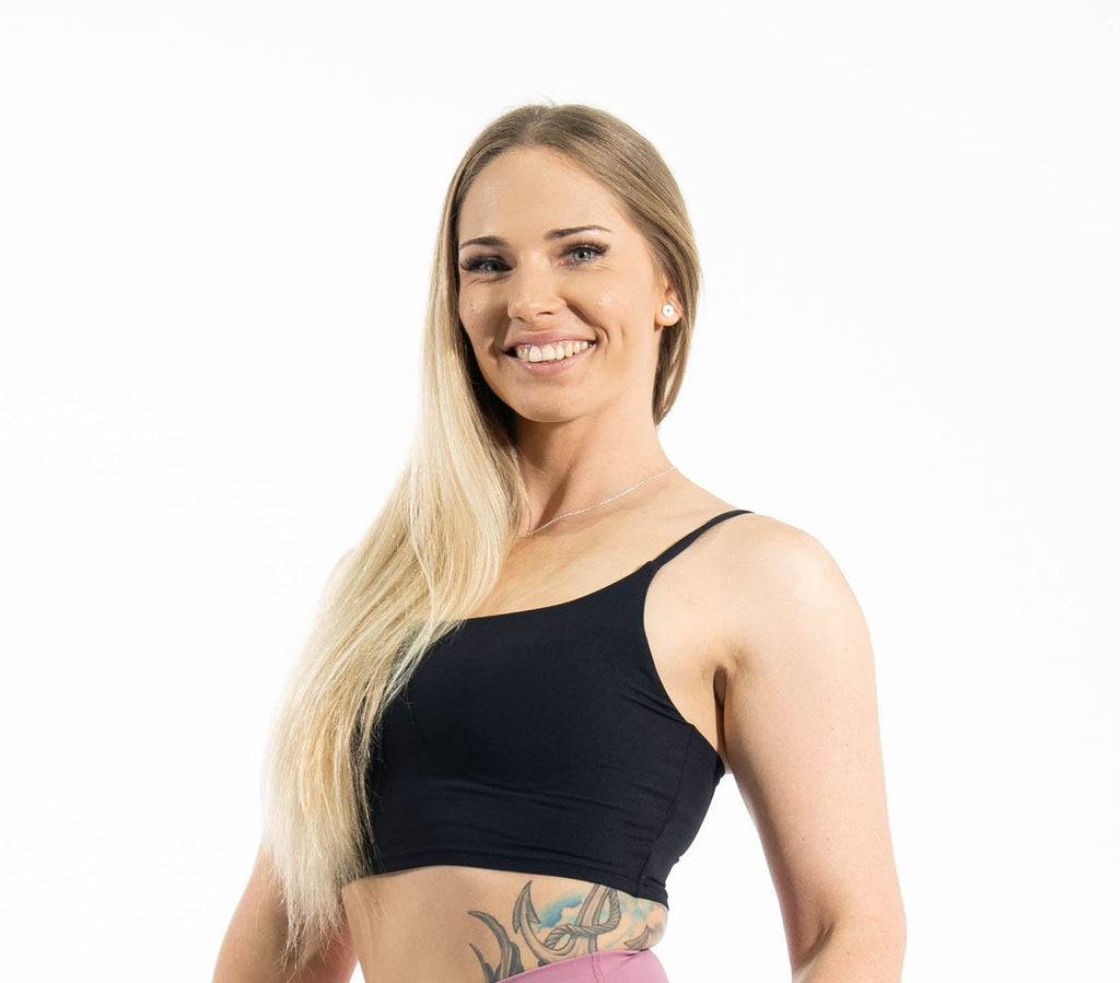 Woman wearing a black sports bra and pink leggings on a white background