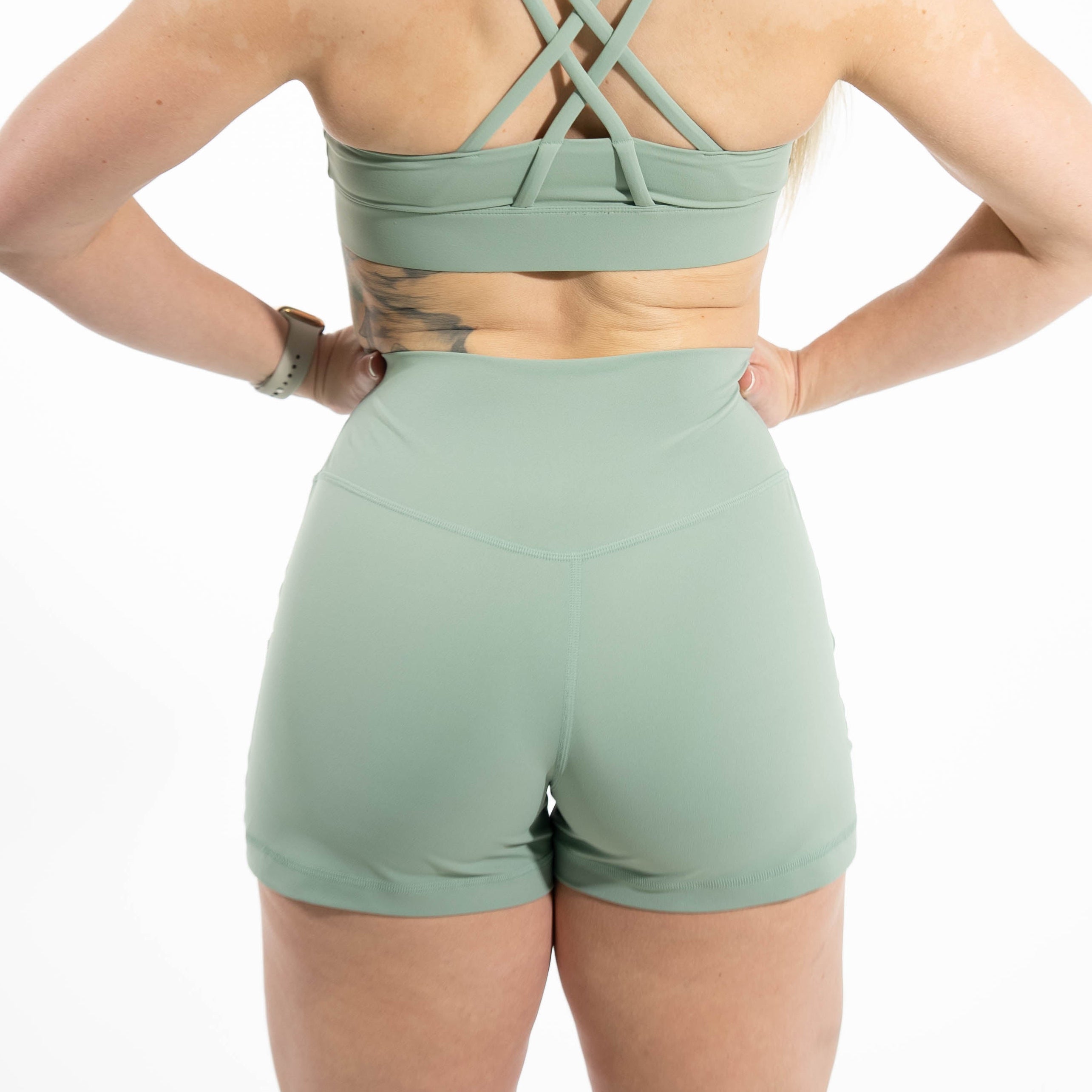 Person wearing a green sports bra and shorts set on a white background
